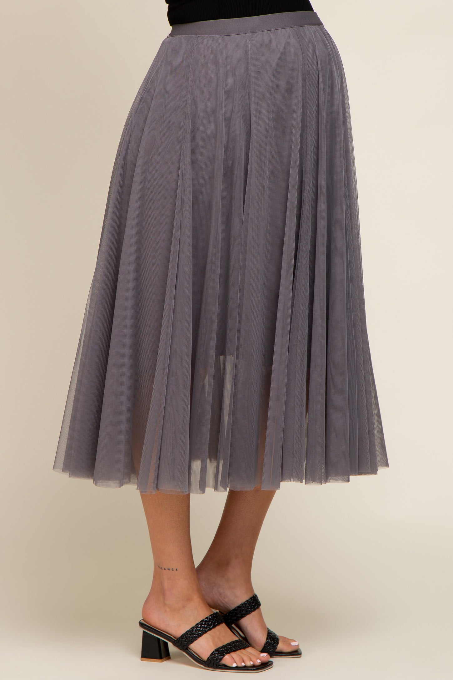 woman wearing a gray tulle midi skirt with pleats and heeled sandals