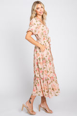 woman wearing a light pink floral maxi dress with short sleeves and a cinched waist, standing in profile
