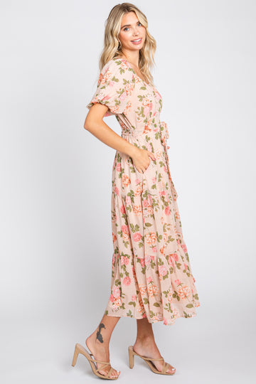 woman wearing a light pink floral maxi dress with short sleeves and a cinched waist, standing in profile
