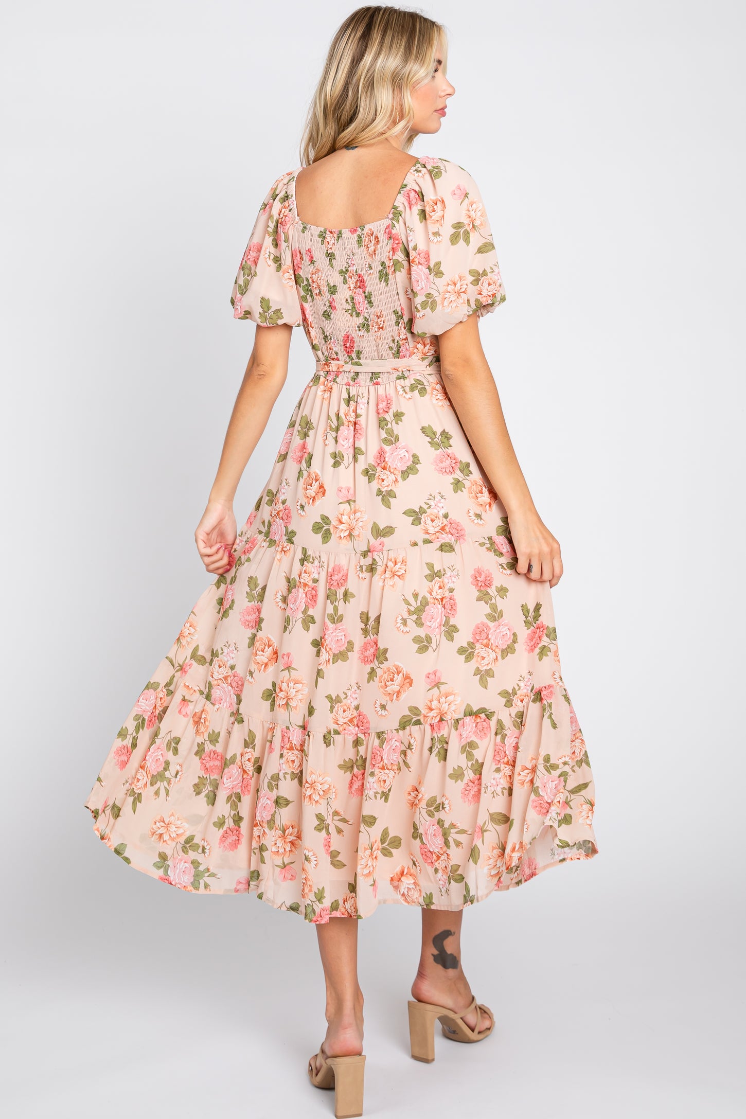 woman wearing a pink floral maxi dress with puff sleeves and a tiered skirt, shown from the back
