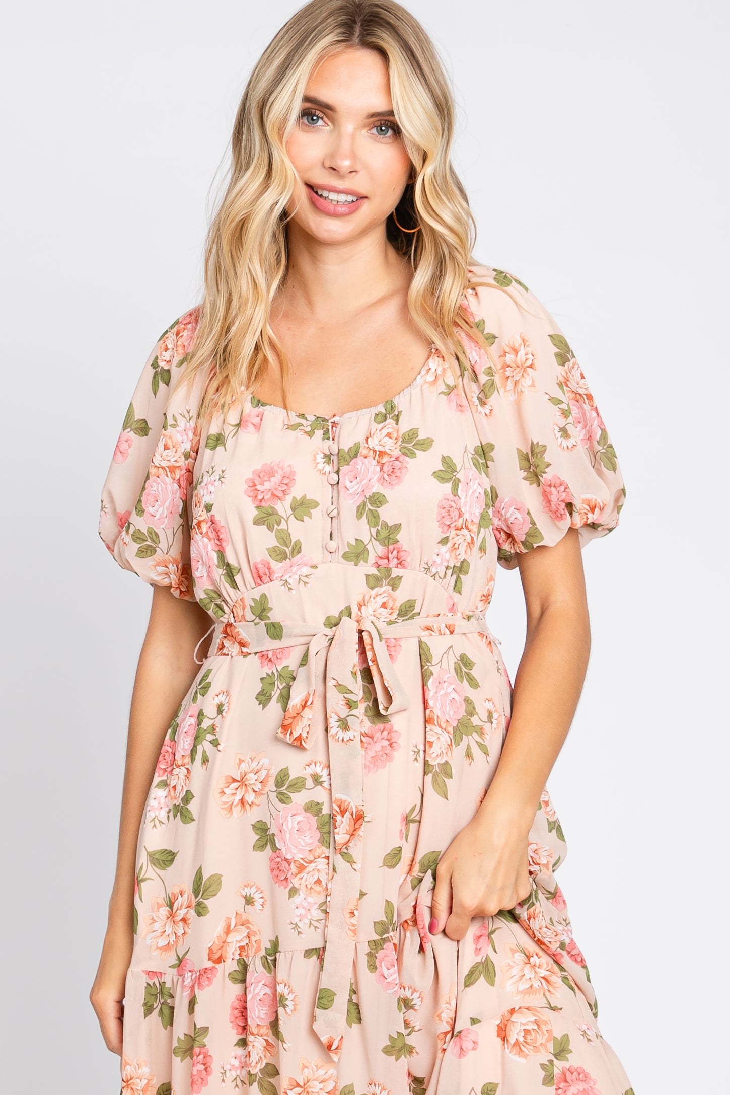 woman wearing a blush floral maxi dress with short puff sleeves and a tie waist detail