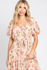 woman wearing a blush floral maxi dress with short puff sleeves and a tie waist detail