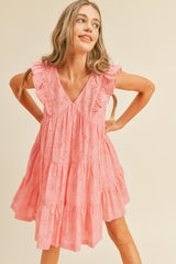 woman wearing a pink ruffled sleeveless dress with a v-neck and tiered skirt