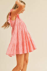 woman wearing a pink eyelet ruffle detail tiered dress, posing sideways with long hair flowing