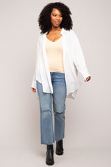woman wearing a white oversized button-up shirt, beige tank top, and distressed blue jeans with black ankle boots