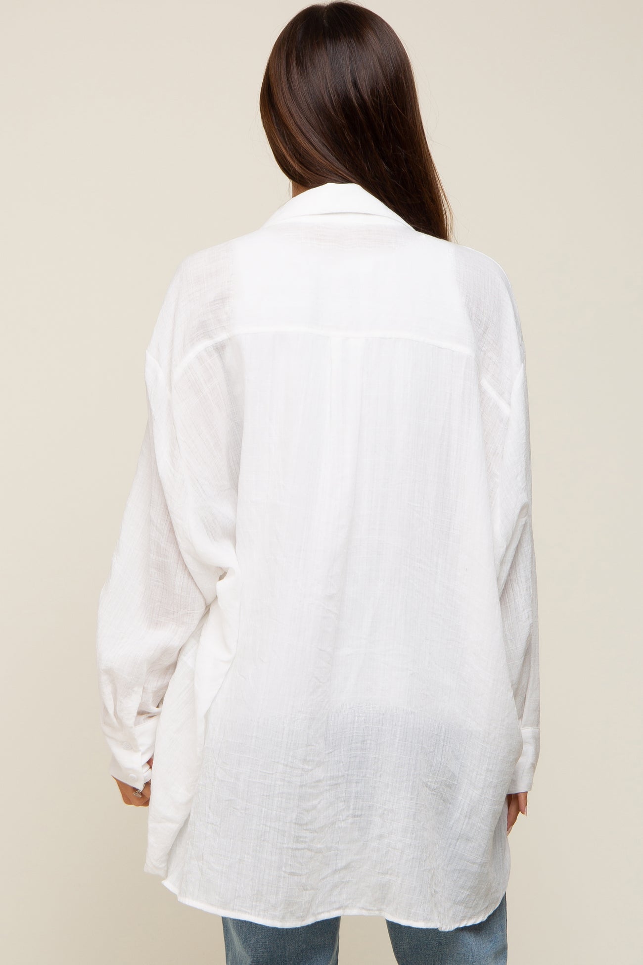 woman wearing a white oversized maternity shirt, showing a loose fit and flowing fabric from the back