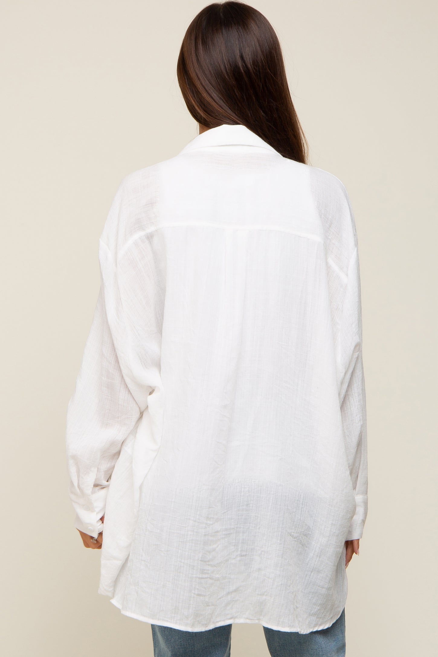 woman wearing a white oversized maternity shirt, showing a loose fit and flowing fabric from the back
