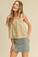 woman wearing a yellow floral crop top with tie straps and a denim mini skirt