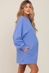 woman wearing a light blue oversized maternity sweatshirt dress with pockets and a visible baby bump