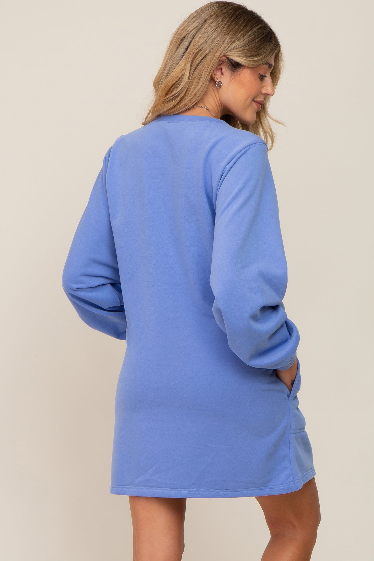 woman wearing a light blue long sleeve maternity dress with pockets, showing the back view