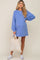 woman wearing a blue long sleeve maternity sweatshirt dress with a baby bump and holding a tote bag