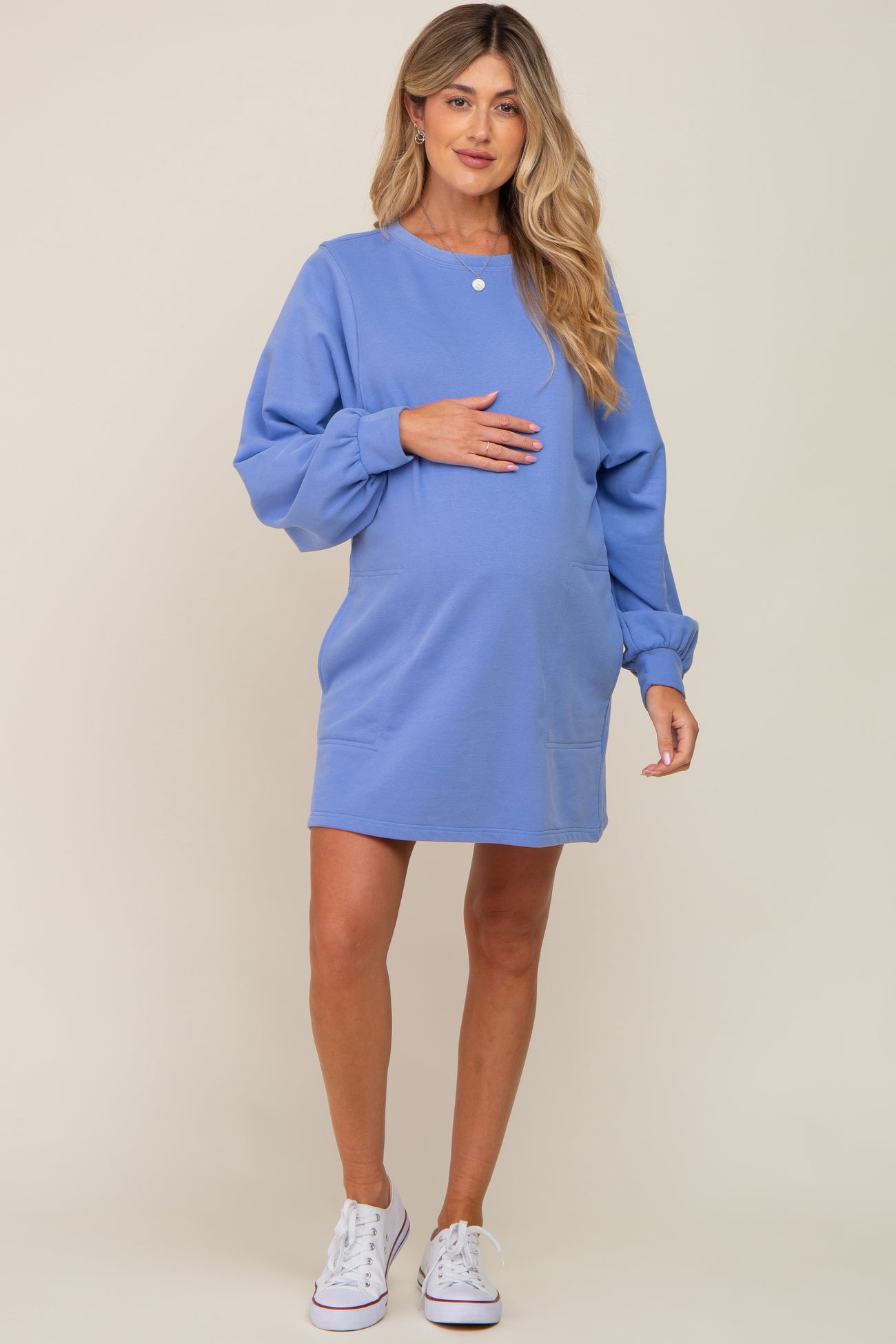 pregnant woman wearing a blue long sleeve maternity sweatshirt dress and white sneakers