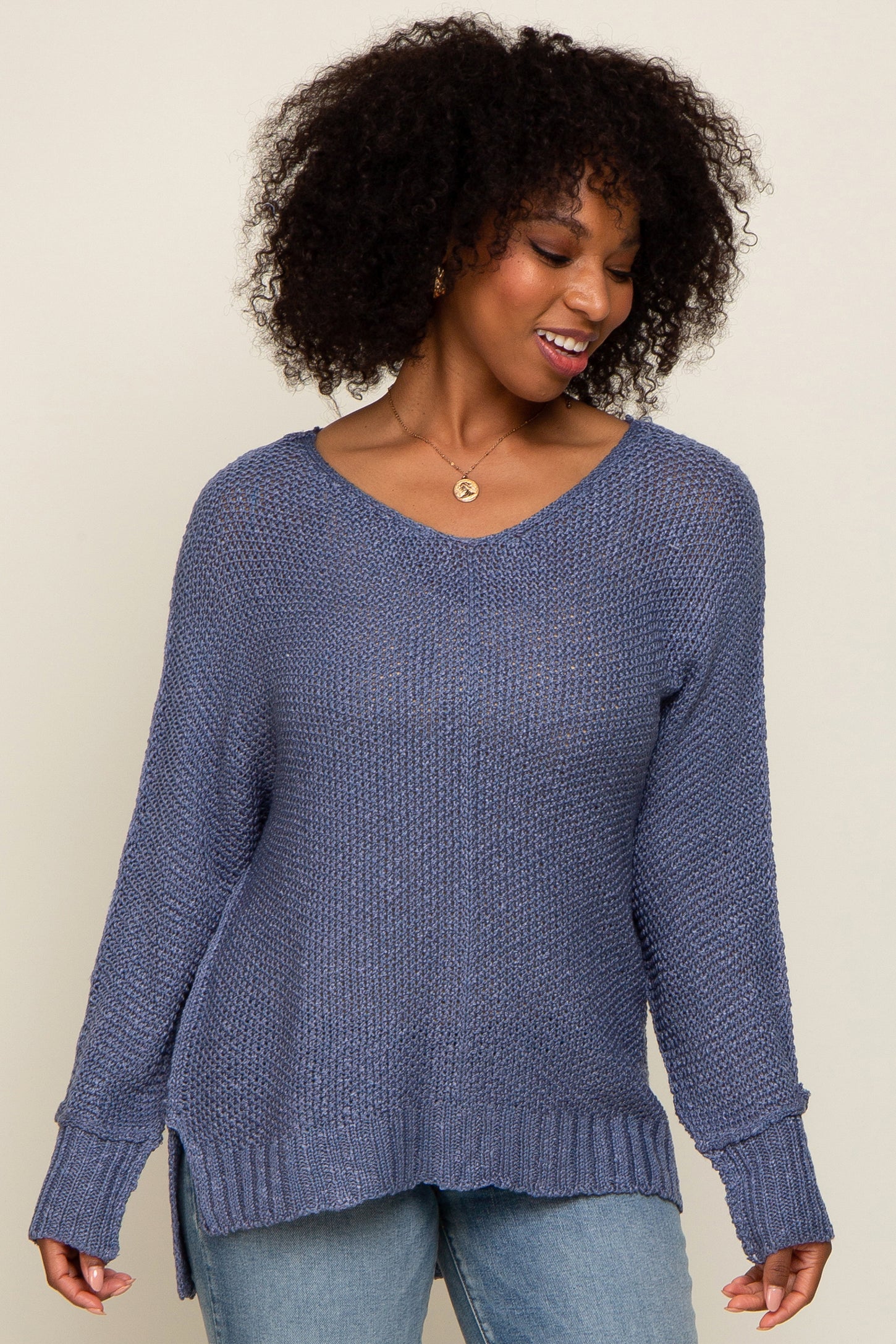 woman wearing a loose-fitting purple v-neck sweater with side slits and long sleeves paired with light blue jeans