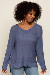 woman wearing a loose-fitting purple v-neck sweater with side slits and long sleeves paired with light blue jeans