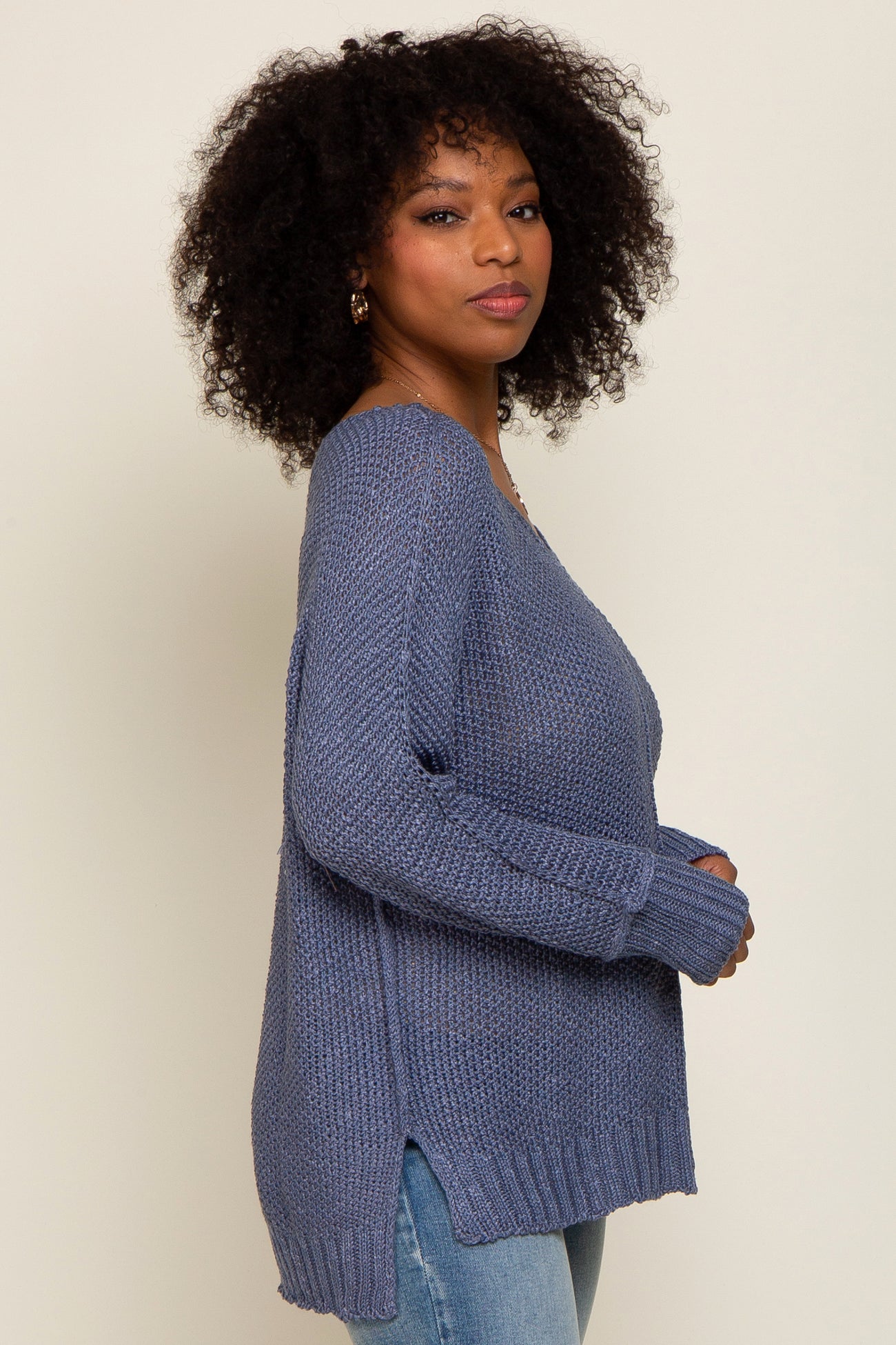woman wearing a navy blue oversized knit sweater with side slits, paired with light wash jeans