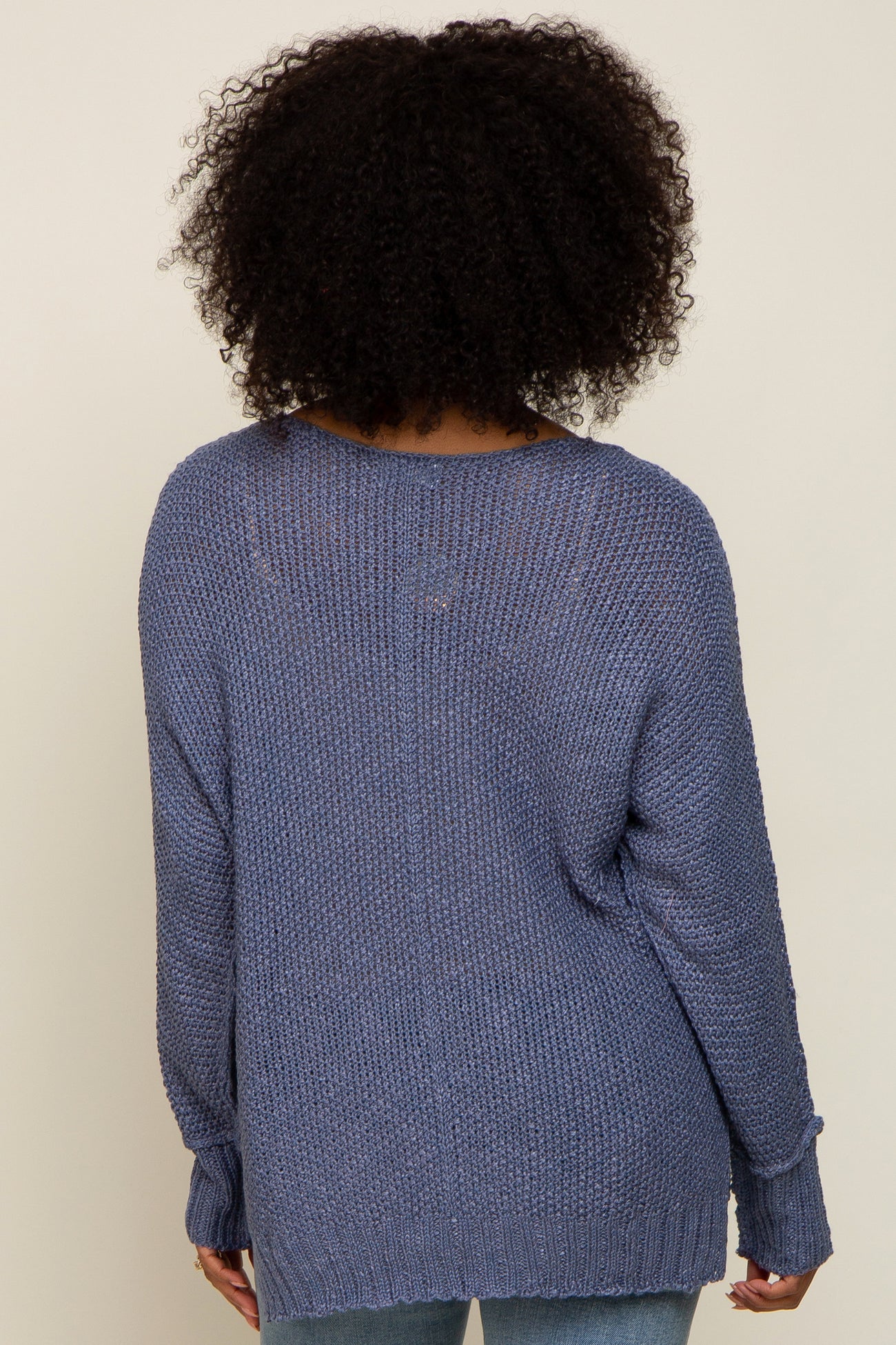 woman wearing a cozy blue oversized knit sweater, view from the back showing relaxed fit and textured fabric