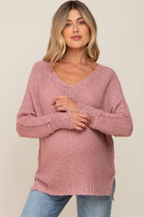 woman wearing a dusty pink v-neck knitted maternity sweater with a visible baby bump