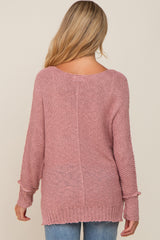 back view of a woman with blonde hair wearing a mauve pink oversized knit sweater and blue jeans