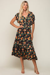 blonde woman wearing a black floral midi dress with orange flowers and ruffle details