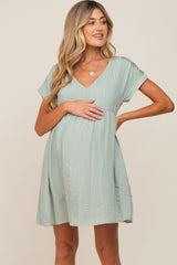 pregnant woman wearing a light green v-neck maternity mini dress with short sleeves