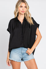woman wearing a black short sleeve button down shirt and denim shorts against a white background