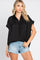 woman wearing a black short sleeve button down shirt and denim shorts against a white background