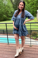 woman wearing a denim maternity dress with a tiered design and holding her baby bump