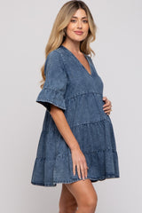 woman wearing a tiered dark denim maternity dress and holding her baby bump