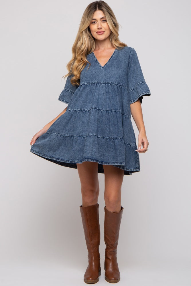 woman wearing a denim tiered maternity dress with a v-neck and flared sleeves, paired with brown knee-high boots