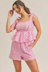 woman wearing pink and white gingham two-piece set with tie-shoulder peplum top and matching shorts