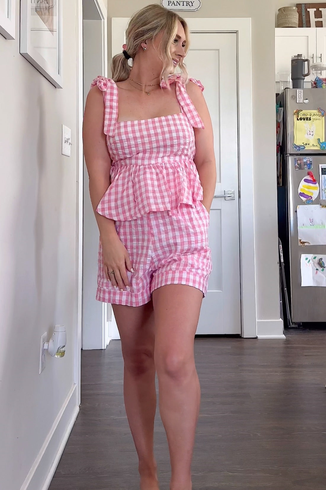 woman wearing a pink and white gingham two-piece set with tie-shoulder top and matching shorts