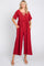 woman wearing a red short sleeve wide leg jumpsuit with lace up neckline and pockets