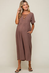 Pregnant woman wearing a mauve lace-up maternity jumpsuit with short sleeves and pockets