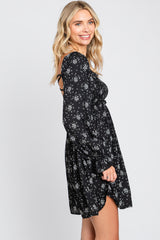 Woman wearing a black long sleeve floral mini dress with a smocked bodice and open back