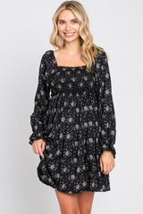 woman wearing a black long sleeve floral mini dress with a smocked bodice and square neckline