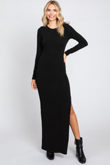 woman wearing a long sleeve black ribbed maxi dress with a side slit and black ankle boots