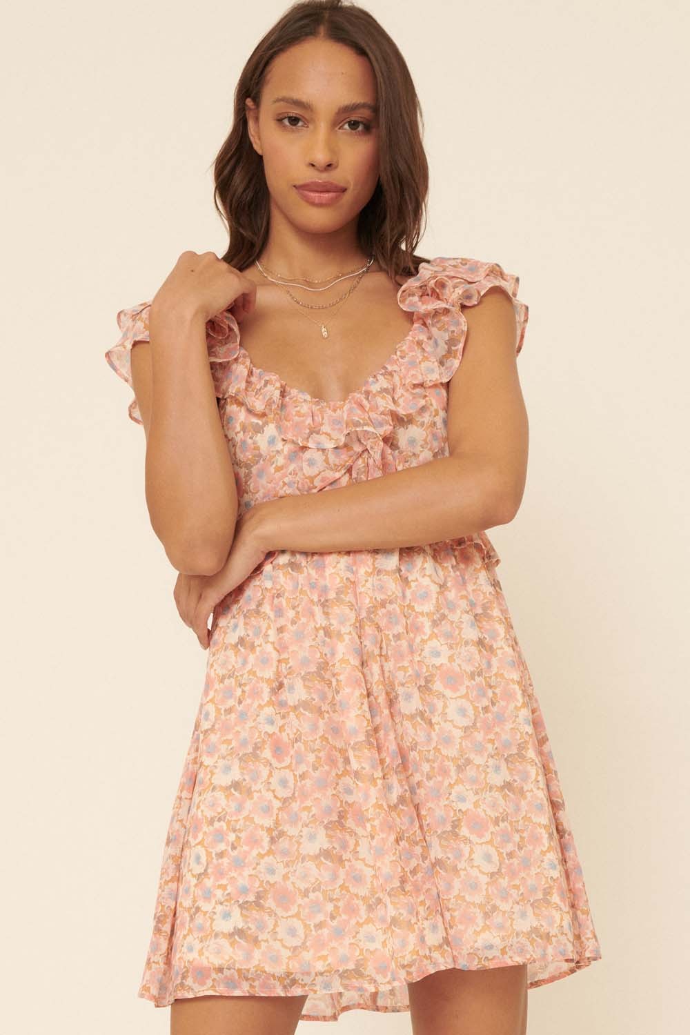 woman wearing a pink floral mini dress with ruffled sleeves and a square neckline