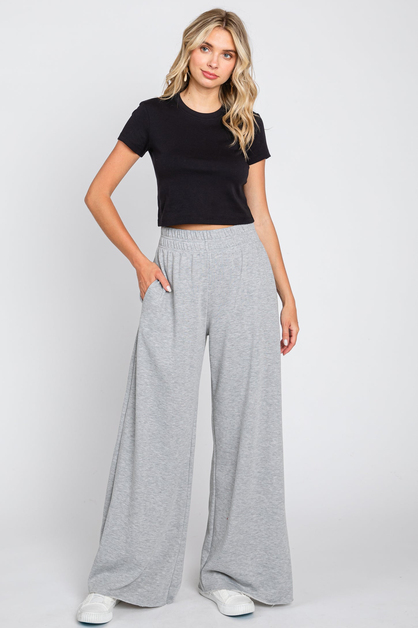 woman wearing a fitted black cropped t-shirt and light grey wide-leg sweatpants with side pockets
