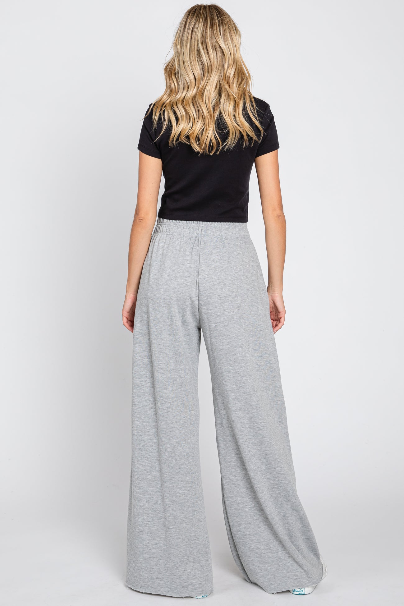 woman wearing a black short sleeve top and light gray wide-leg pants, view from the back