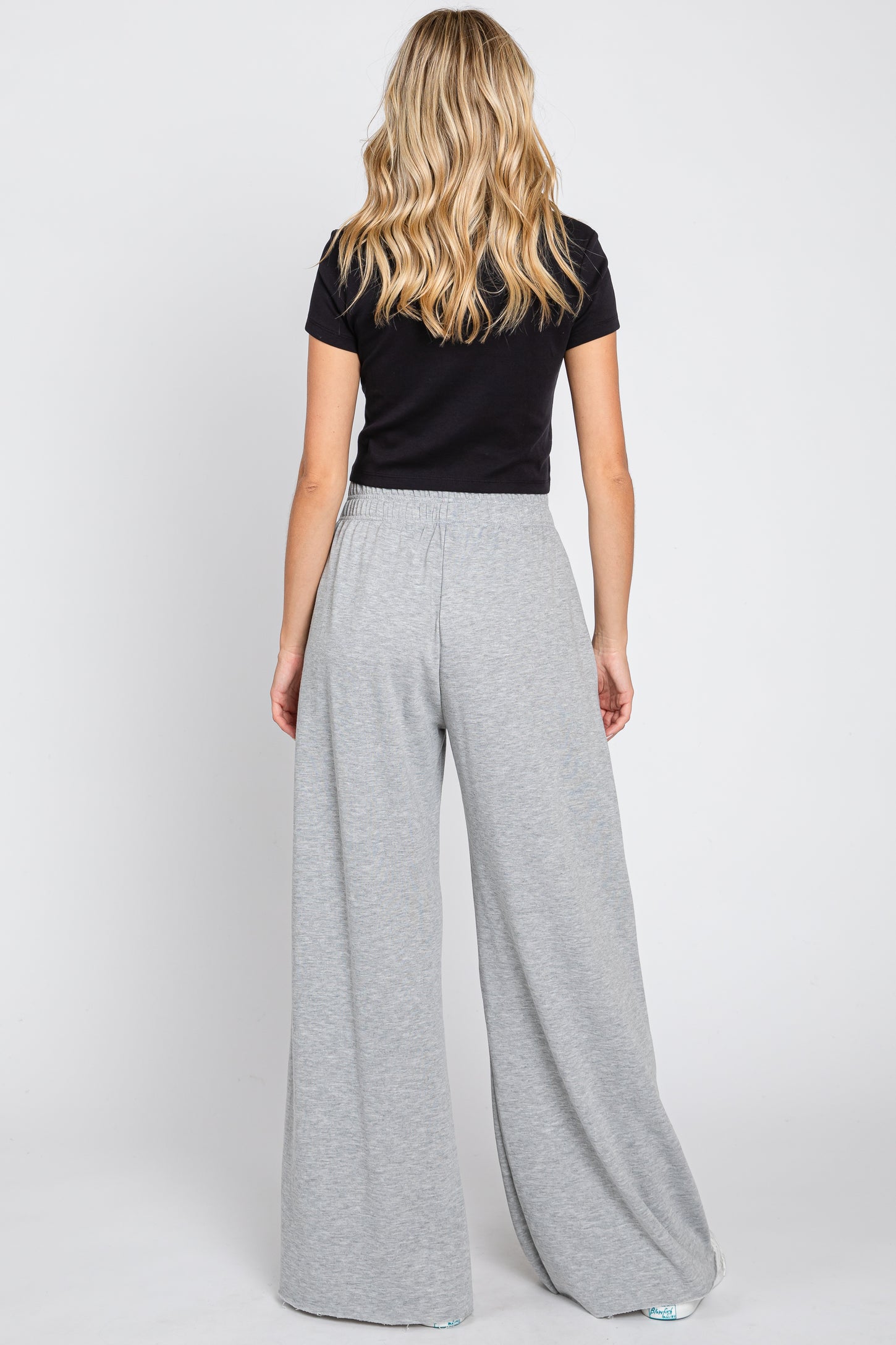 woman wearing a black short sleeve top and light gray wide-leg pants, view from the back