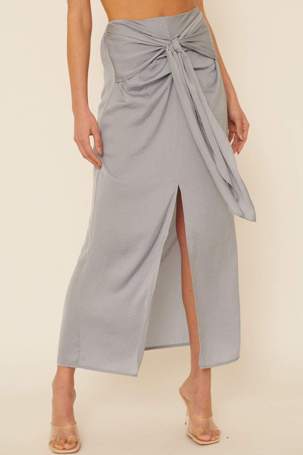 woman wearing a light gray wrap skirt with a front knot detail and a thigh-high slit