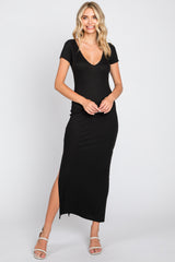 woman wearing a black ribbed maxi dress with a deep v-neck and side slit, standing and smiling