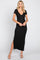 woman wearing a black ribbed maxi dress with a deep v-neck and side slit, standing and smiling