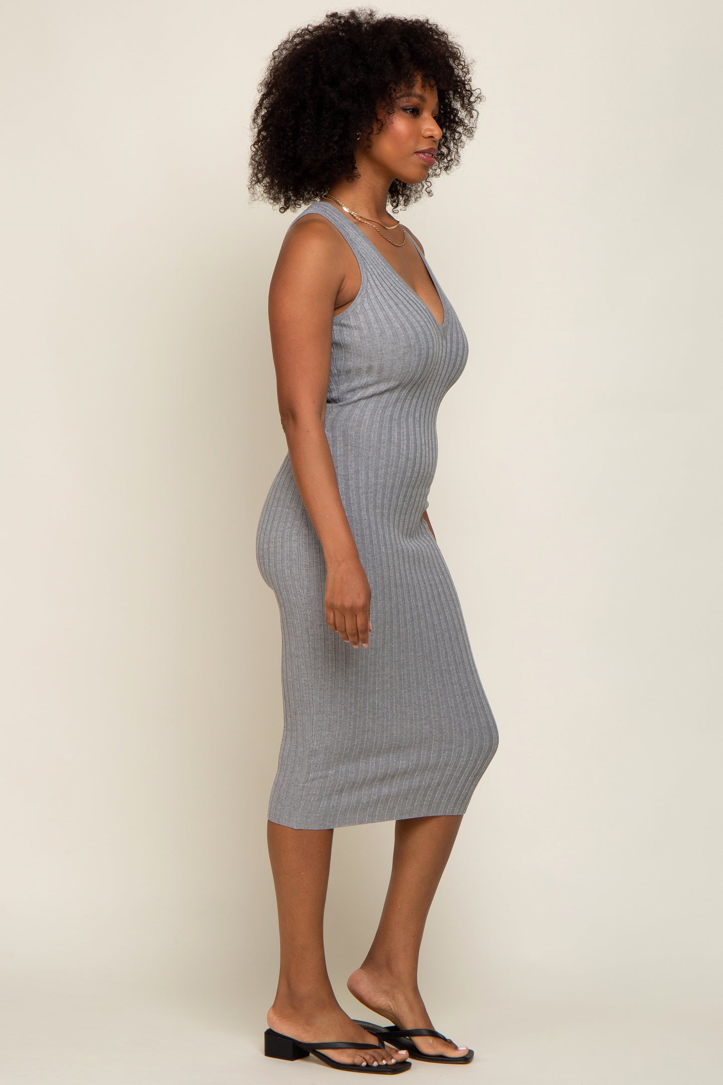 woman with afro hair wearing a grey ribbed sleeveless midi dress and black sandals