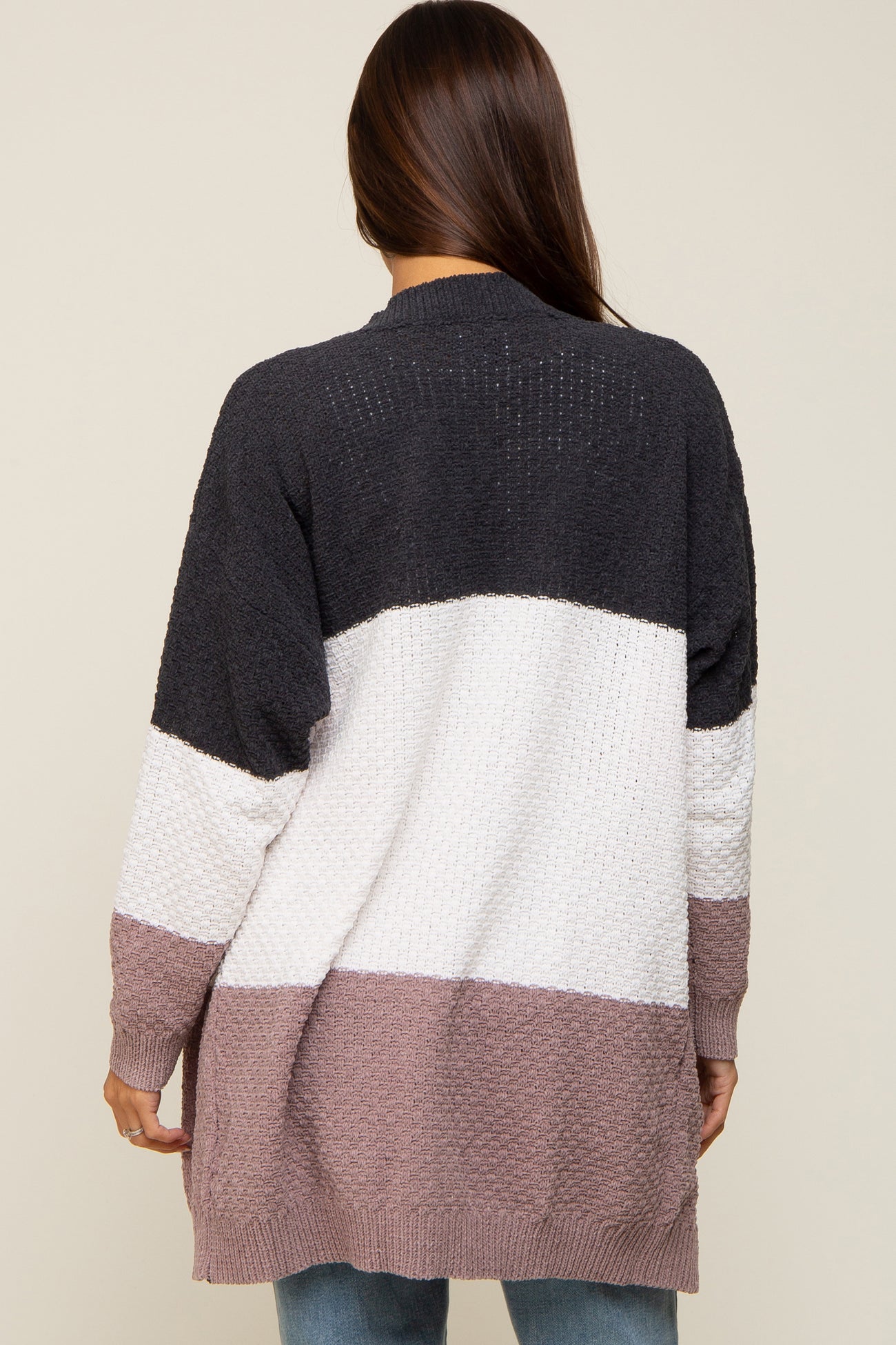 Back view of woman wearing a long colorblock knit cardigan in charcoal, white, and mauve
