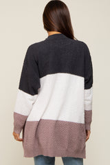 Back view of woman wearing a long colorblock knit cardigan in charcoal, white, and mauve