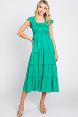 woman wearing a green smocked tiered midi dress with ruffle sleeves and tan heels