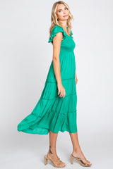 woman wearing a green smocked tiered midi dress with ruffle sleeves and tan heeled sandals
