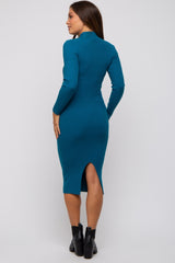 woman wearing a teal ribbed maternity dress with long sleeves and a back slit
