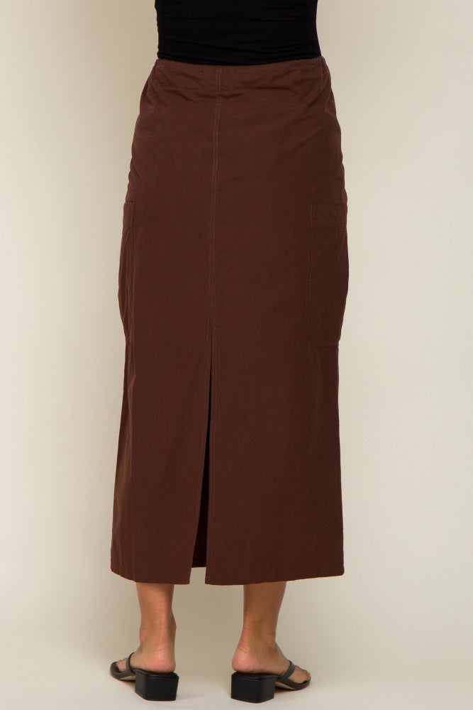 back view of a woman wearing a long brown cargo maxi skirt with a center slit and side pockets